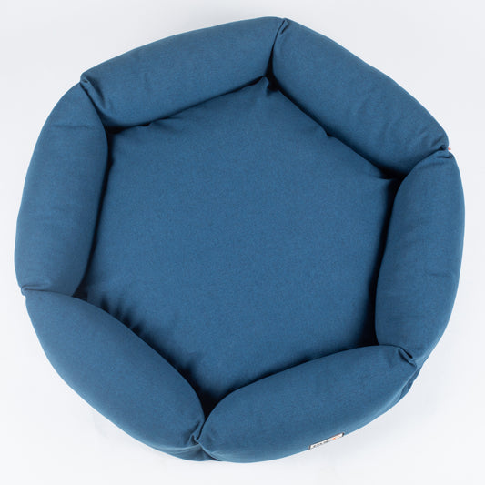 A navy blue round pet bed made of fabric, with a soft cushion inside.