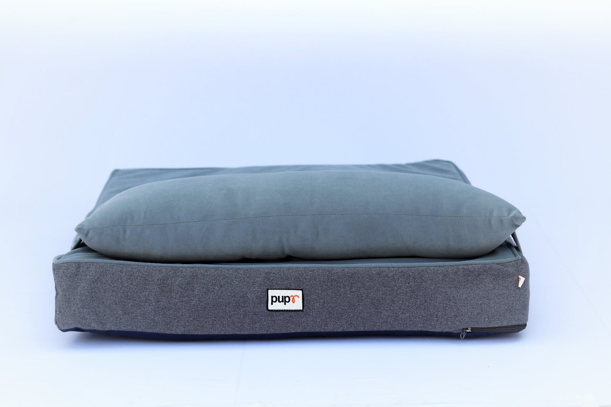 A gray pet pillow with a plush top and a label showing the brand name 'PUPR' on the bottom.