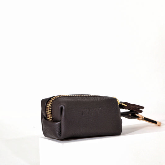 A brown waste bag holder with a gold zipper and a keychain attachment, displayed against a white background.