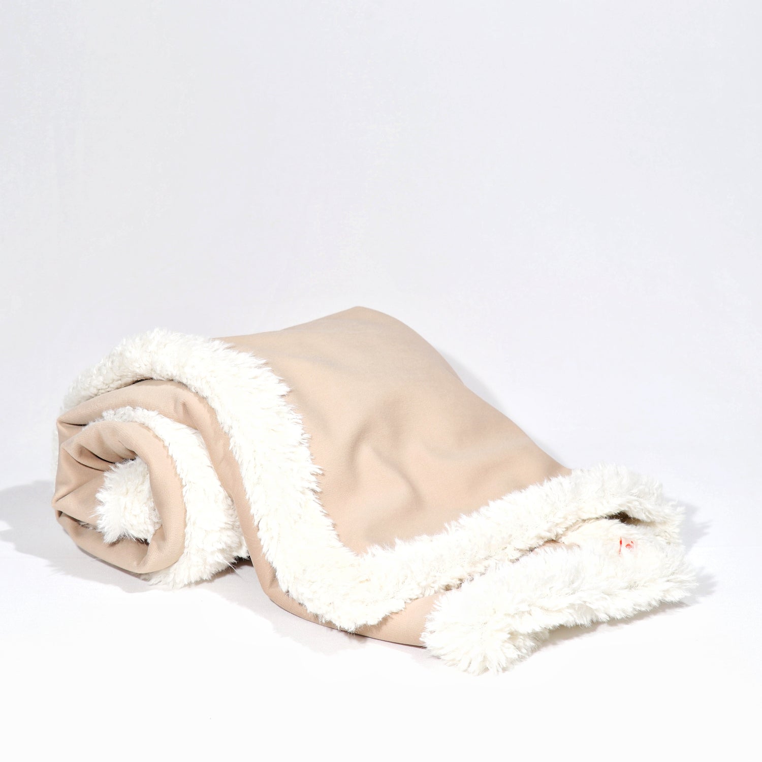 A rolled-up beige dog  blanket with a white fluffy edge on a white background.